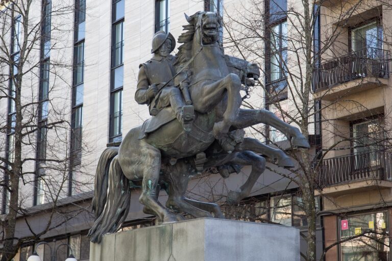 Two armoured cavalrymen riding. The horses are rearing wildly, neighing and kicking the air with their front legs, while the riders hold the reins tightly.