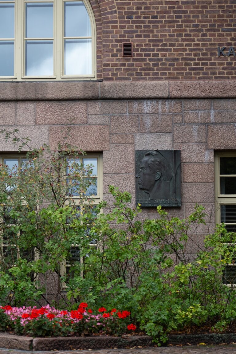 A bronze relief of a man's side profile placed on the wall of a building.