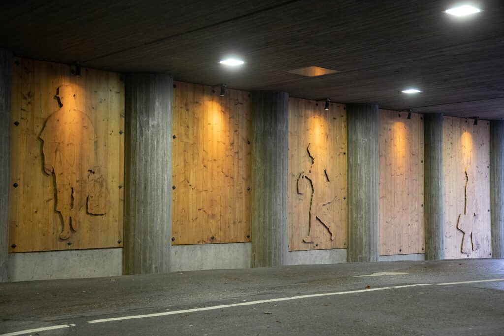 Three wooden reliefs depicting people walking.