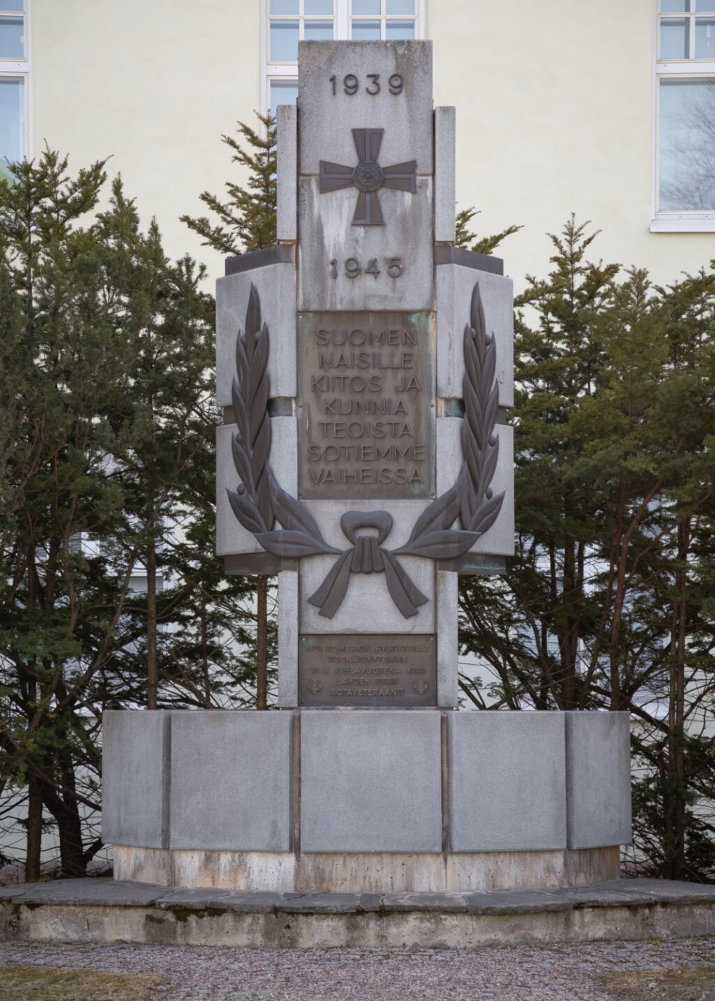 Granite monument with bronze cross, rosette, dates 1939 and 1945, and text plaques.