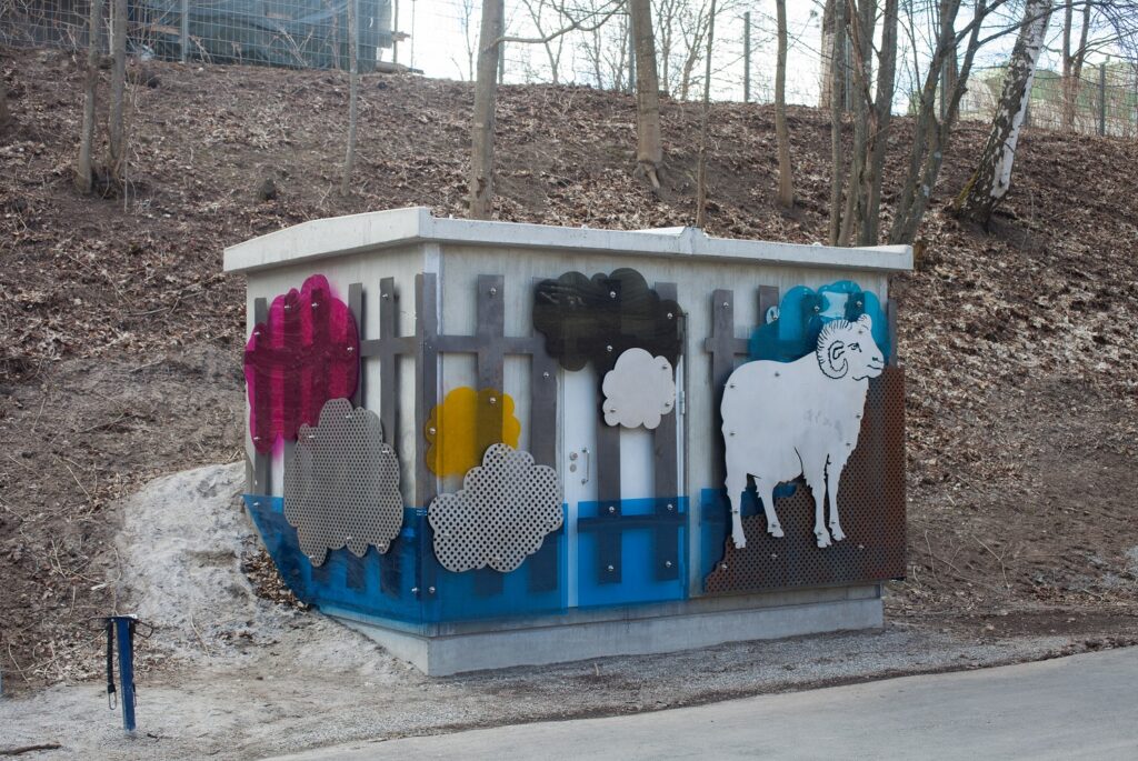 A relief-like, ram-themed colorful artwork attached to an electrical transformer.