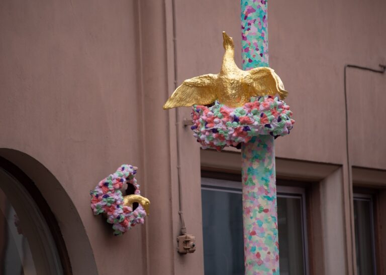 Sculptures depicting golden geese attached to the wall and street pole.