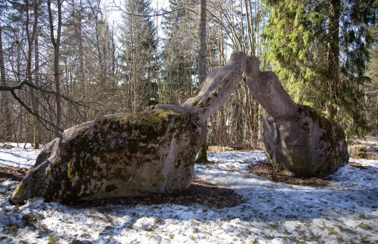 A concrete sculpture placed in the park depicting two human figures rising from boulders and reaching towards each other.