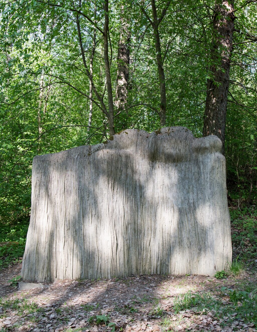 A concrete sculpture placed in the park, depicting a resting female figure growing from a willow platform.