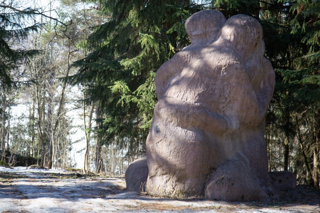 Puistoon sijoitettu betoninen veistos, joka kuvaa kahta halaavaa ihmishahmoa.