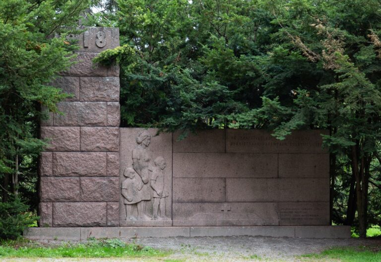 A granite angular monument with a relief of two children holding their mother's hand.