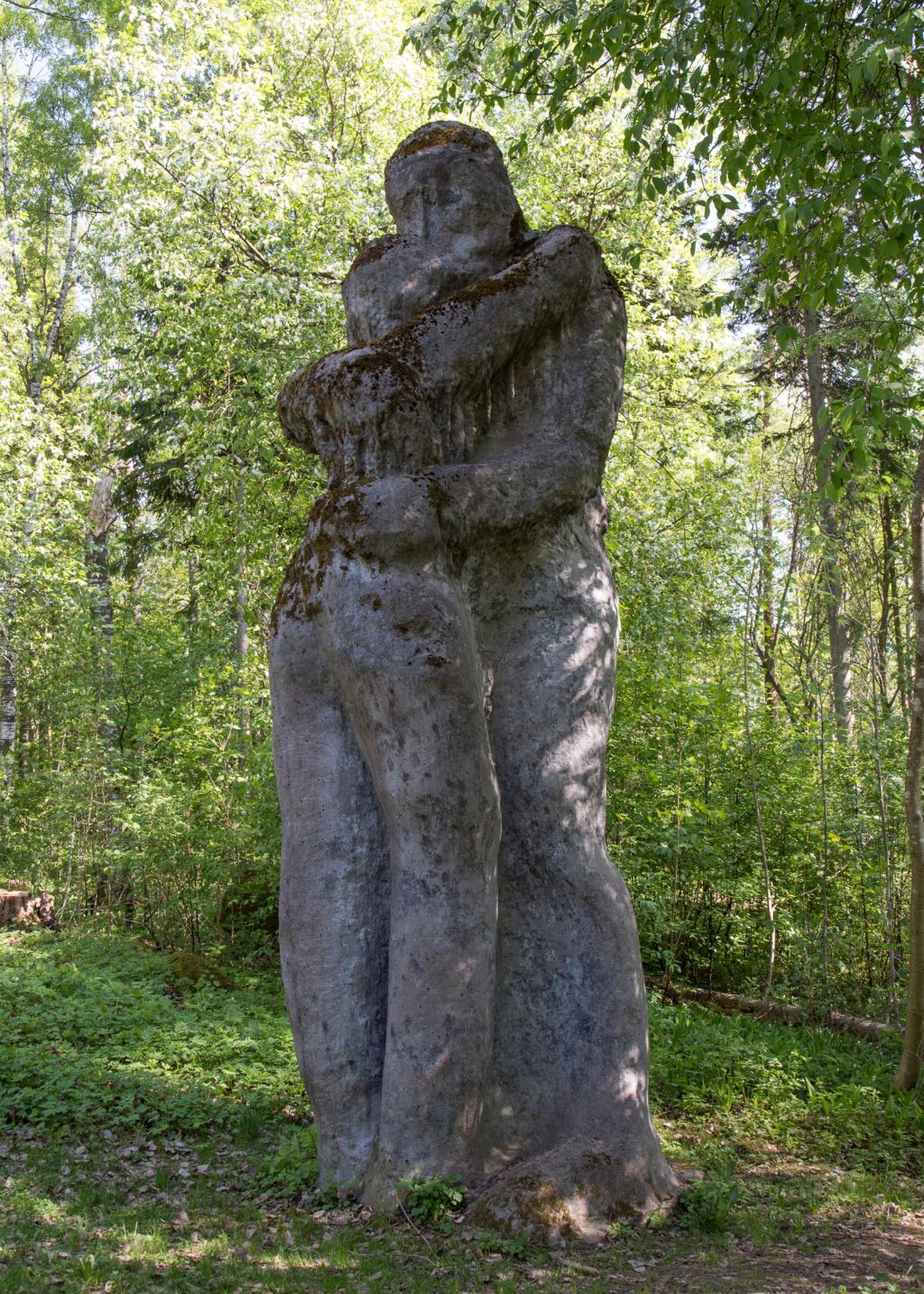 A concrete sculpture placed in the park depicting two hugging human figures.