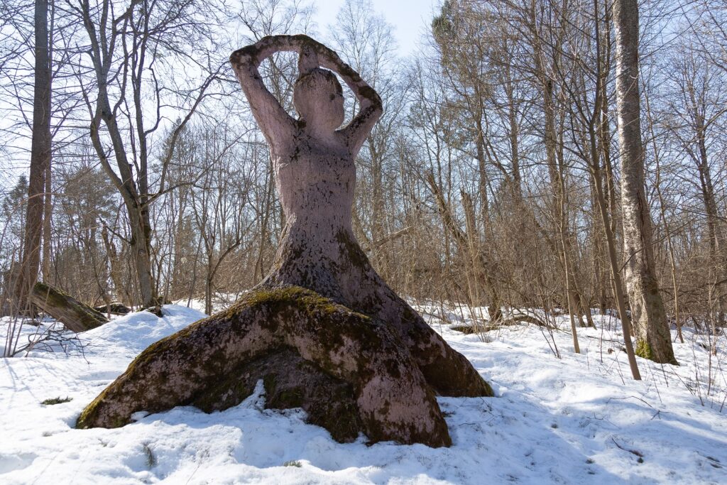 A concrete sculpture placed in the park depicting a human figure rising from a stump.