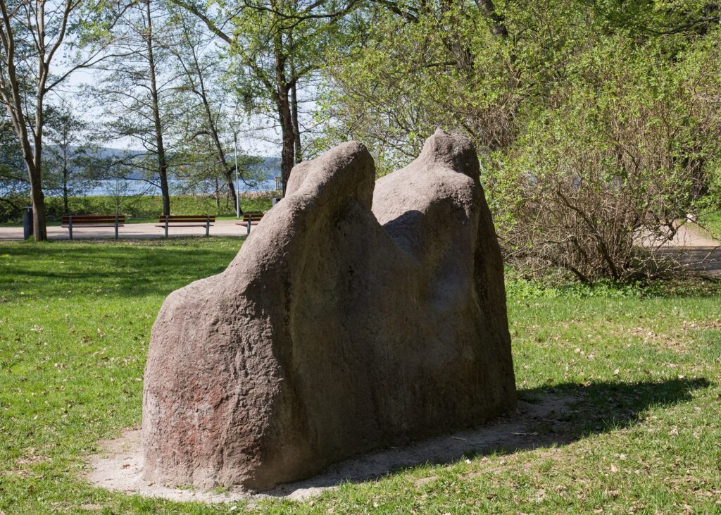 A concrete sculpture placed in the park depicting a naked female figure resting on a stone.