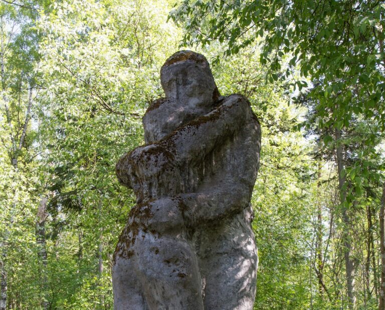 A concrete sculpture placed in the park depicting two hugging human figures.