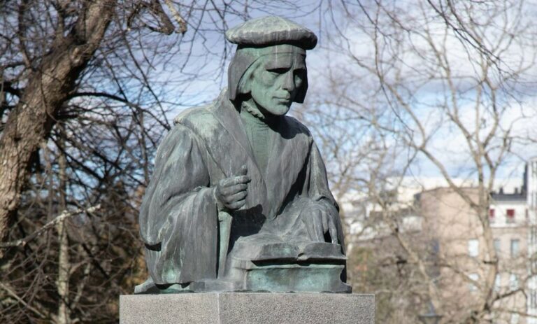 Bronze sculpture depicting a bust of a man holding a book.