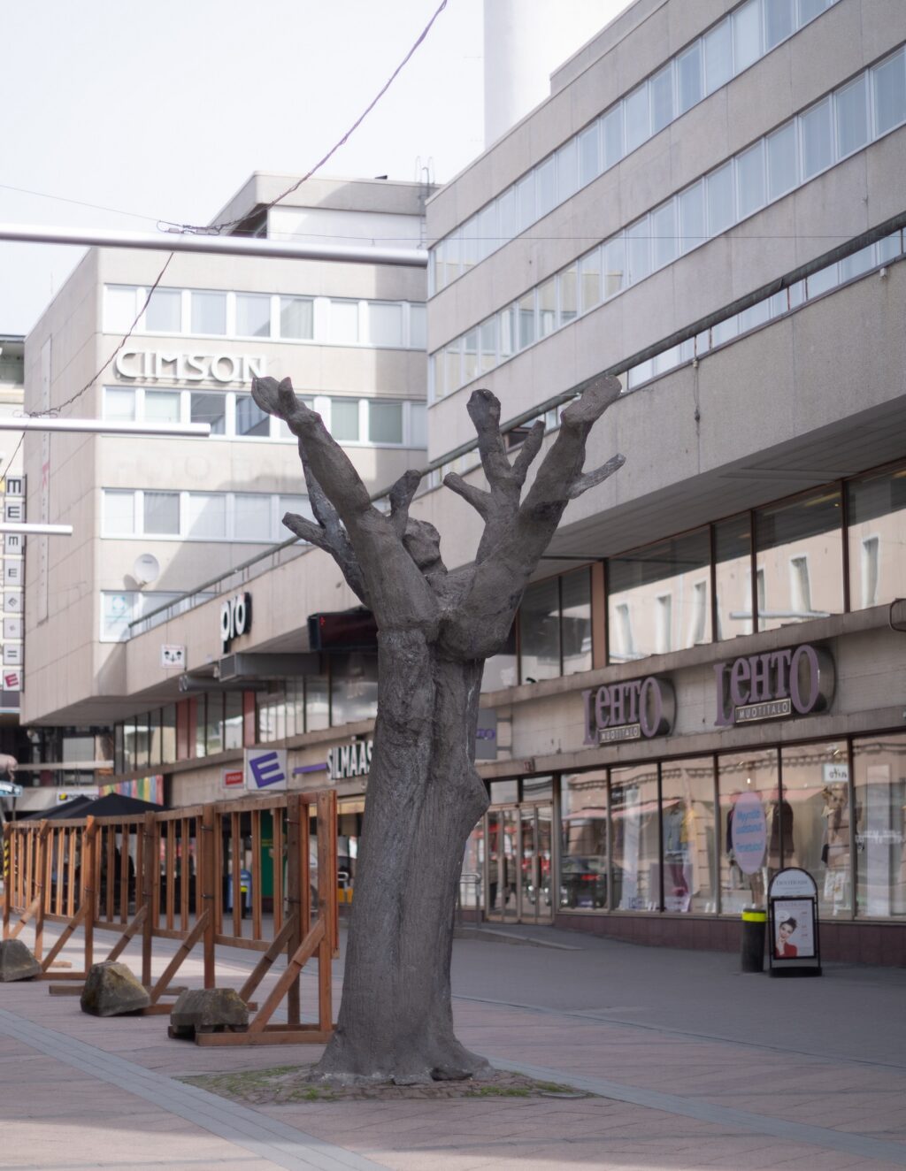 A concrete sculpture placed on the street depicting a human figure lying on a tree trunk.