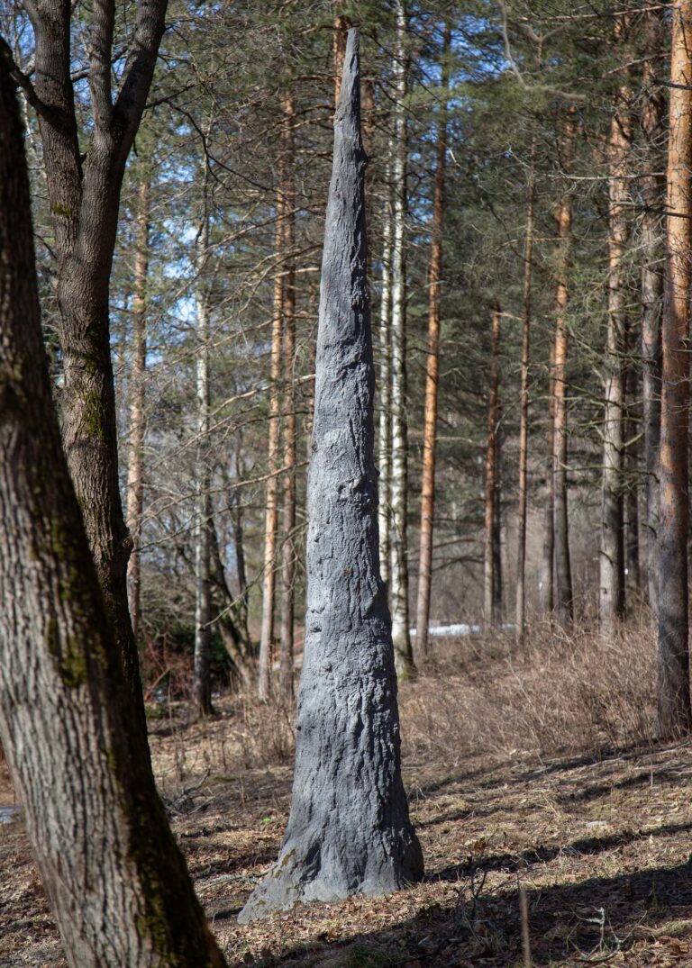 A concrete sculpture placed in the park depicting the trunk of a tree tapering upwards.