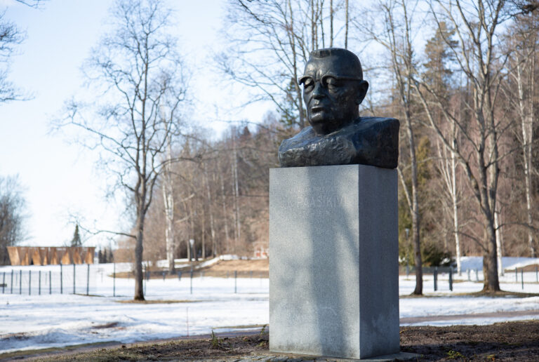 A bronze sculpture depicting a bust of a man wearing eyeglasses.