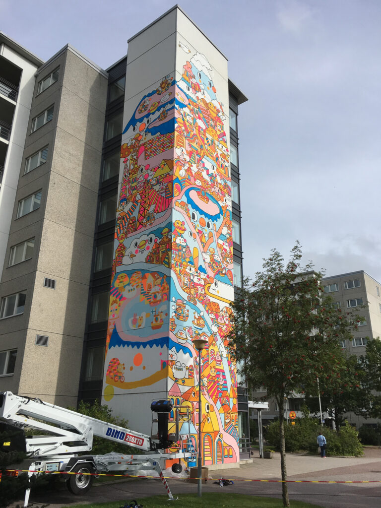 A colorful, cartoon-like mural painted on two walls of the apartment building's elevator structure.