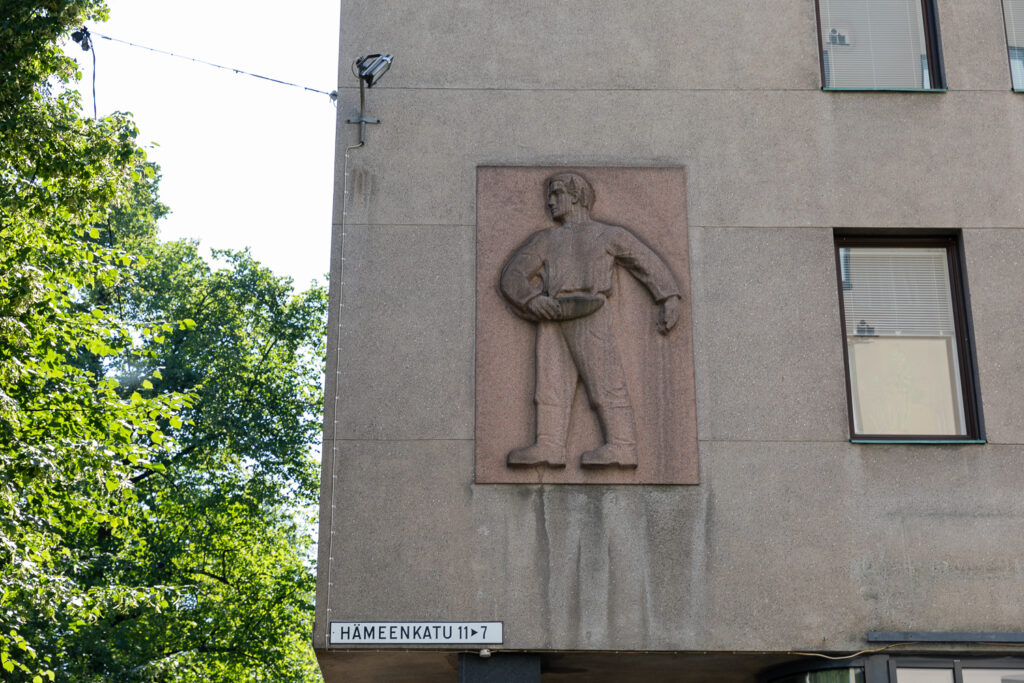 Stone relief on a building's wall depicting a person carrying a container.