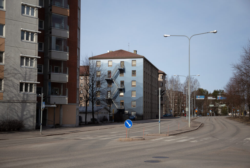 A building by the roadside with a blue-toned mural.