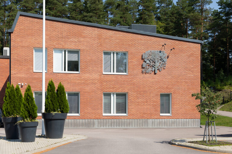 Red brick building with a steel wood relief on the wall at the second floor.