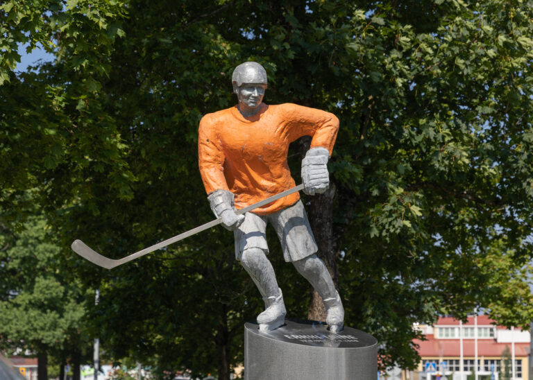 Aluminum ice hockey player statue wearing an orange-painted jersey.