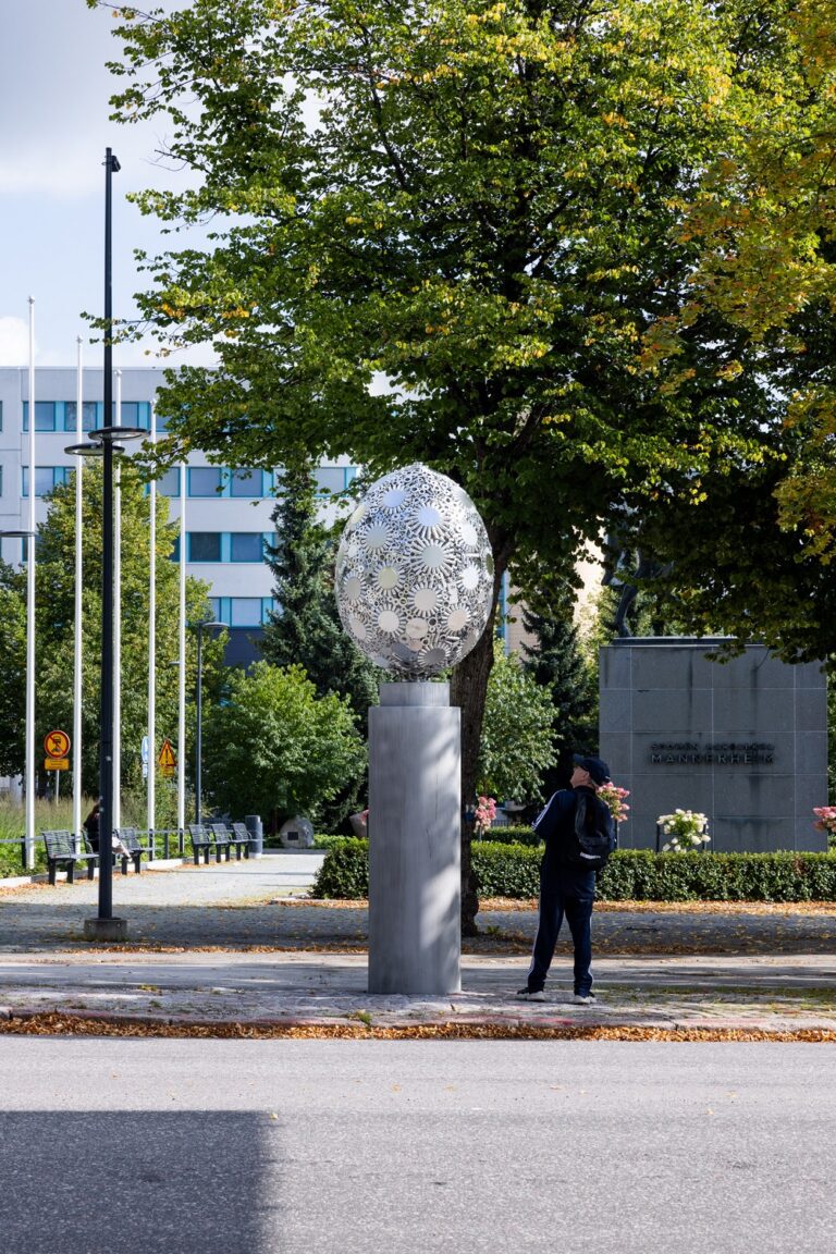 An egg-shaped metal sculpture consisting of metal parts arranged in lace-like patterns.