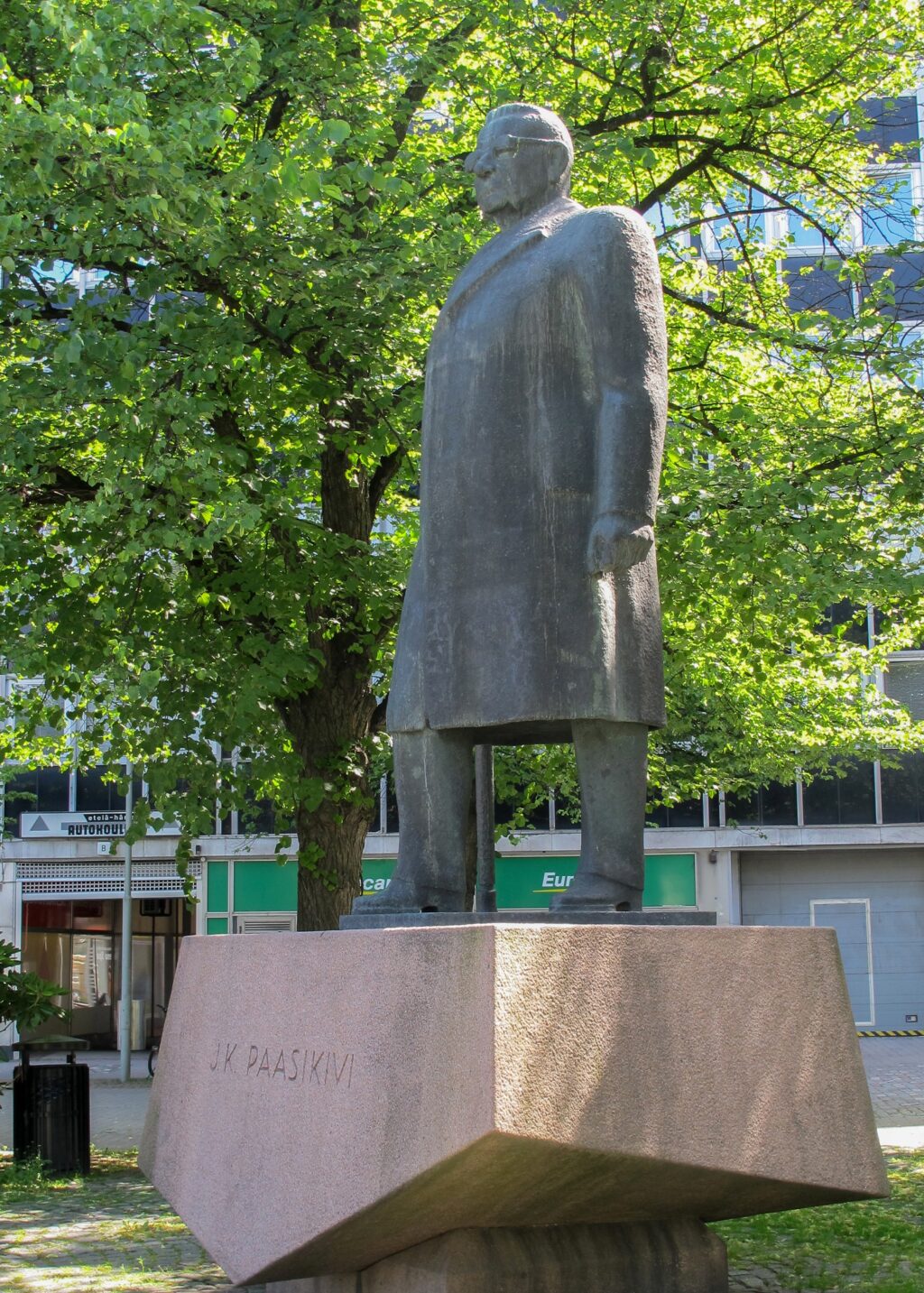 A bronze statue of a bespectacled man standing on a stone plinth.