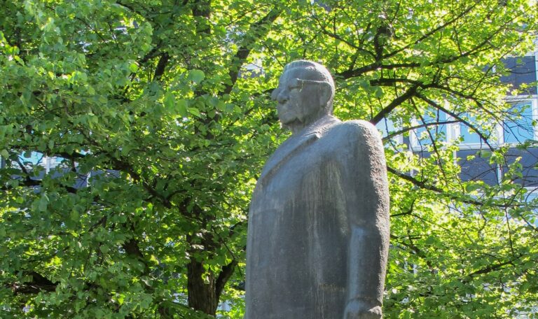 A bronze statue of a bespectacled man.